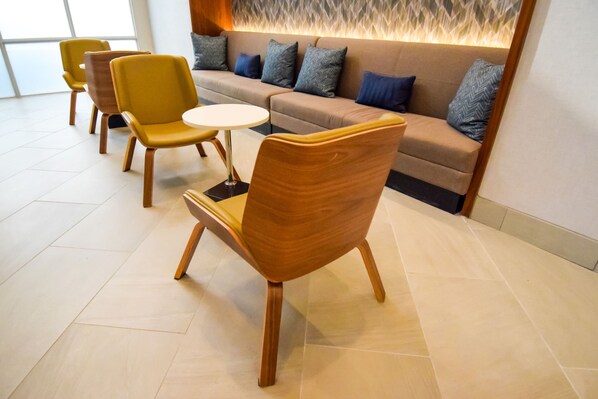Un espace de détente moderne comprenant un canapé, des fauteuils et une petite table.