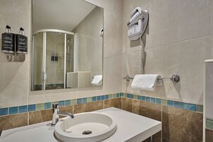 A bathroom with a sink, mirror, and a hairdryer mounted on the wall.