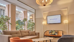 A modern lounge area with a sofa, two chairs, a small table, and a television displaying 'HARRYCULTURE ENGAGES'.