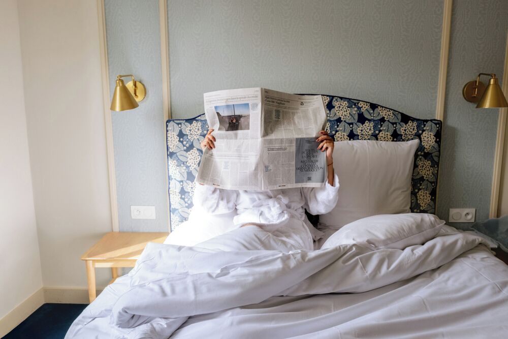 A bed with a patterned headboard, a bedside table, and two wall-mounted lamps.