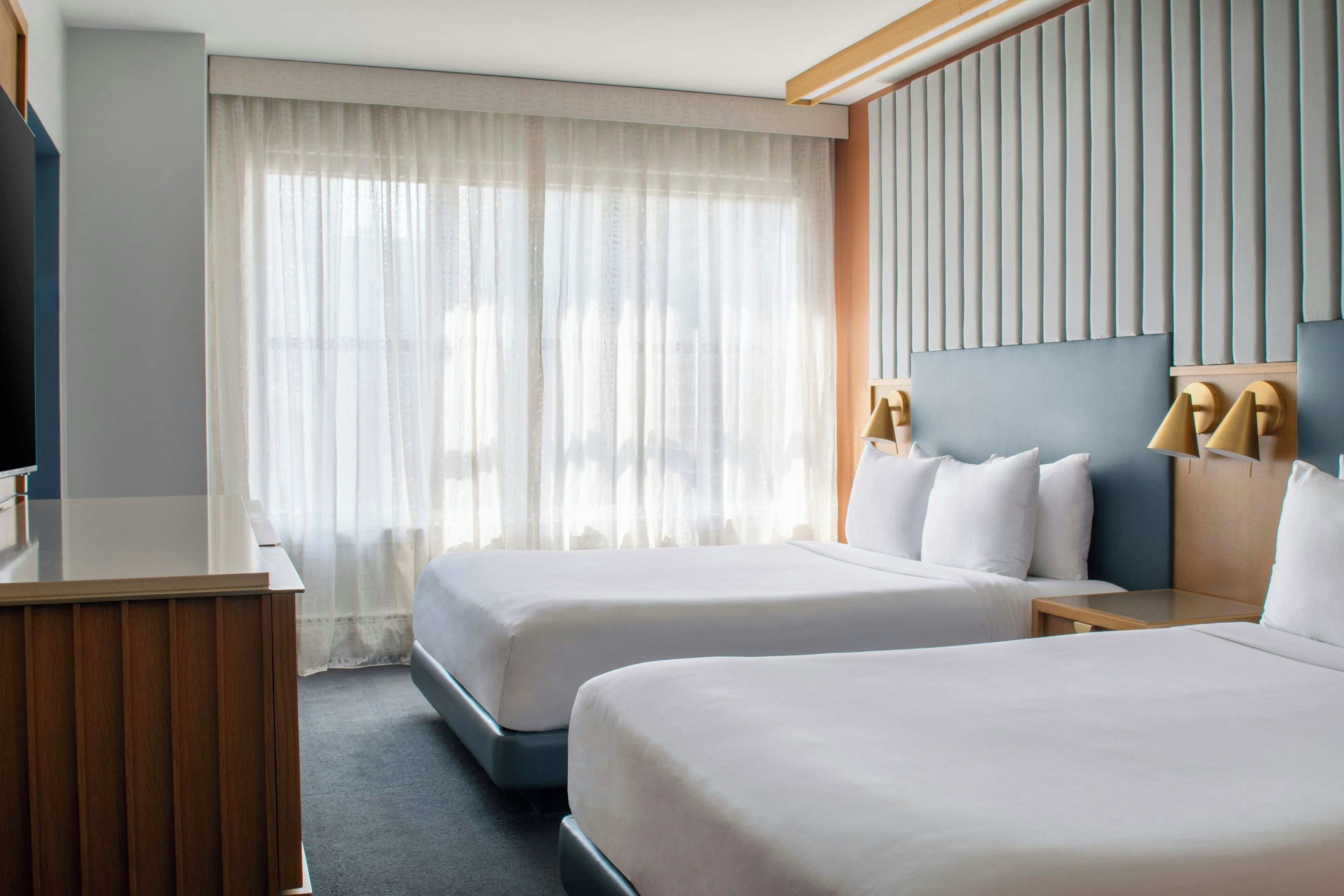 Een hotelkamer met twee bedden, een bureau en een televisie.