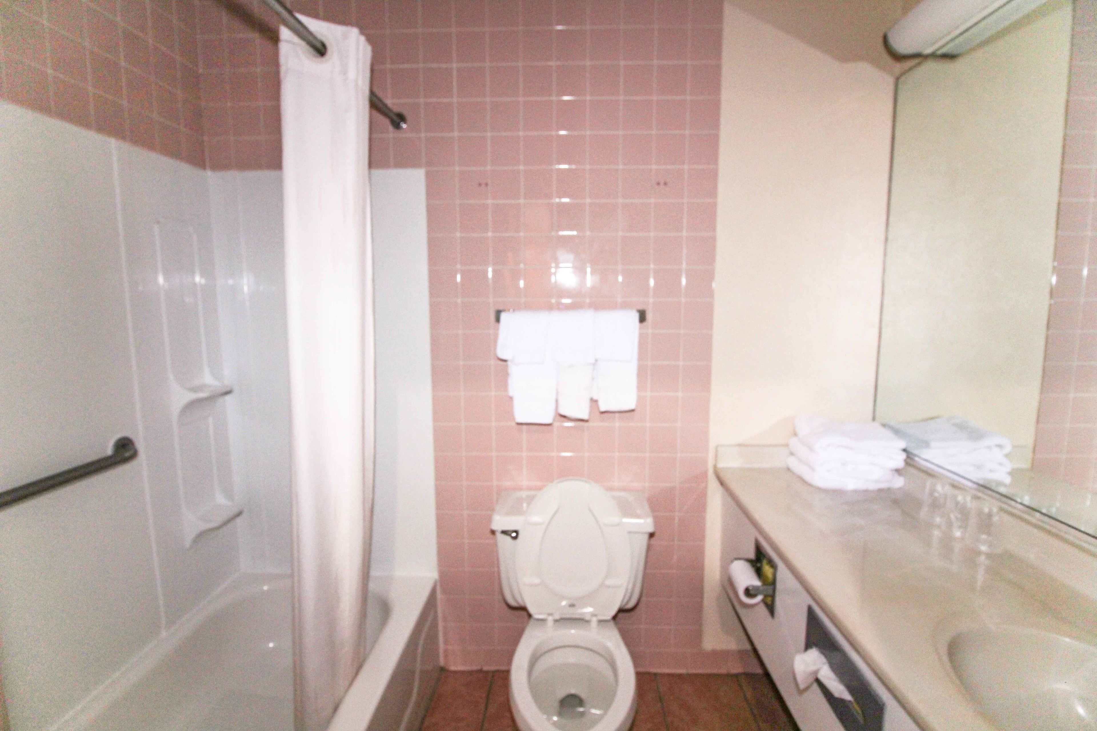 Un baño con inodoro blanco, zona de ducha y lavabo con toallas.