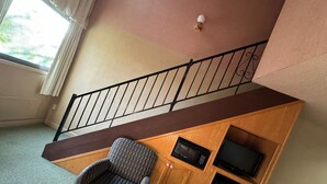 A room with a wooden desk, a chair, a television, and a microwave. - FairBridge Inn & Suites at West Point (Highland Falls)