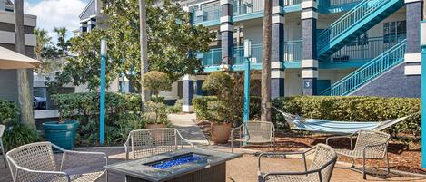 A hotel courtyard with outdoor seating, a fire pit, and a staircase.