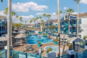 A hotel with a swimming pool, palm trees, and outdoor seating areas. - Sonesta ES Suites Orlando - Lake Buena Vista (Orlando)