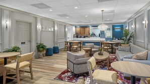 A modern hotel lobby with a bar, seating areas, and a reception desk.