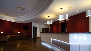 A reception area with a curved ceiling, recessed lighting, a reception desk, and a seating area with tables and chairs. - Steigenberger Hotel Dortmund (Dortmund)