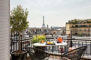 A balcony with a table, chairs, and a view of the Eiffel Tower. - Hotel Atala Champs Elysées (Paris)