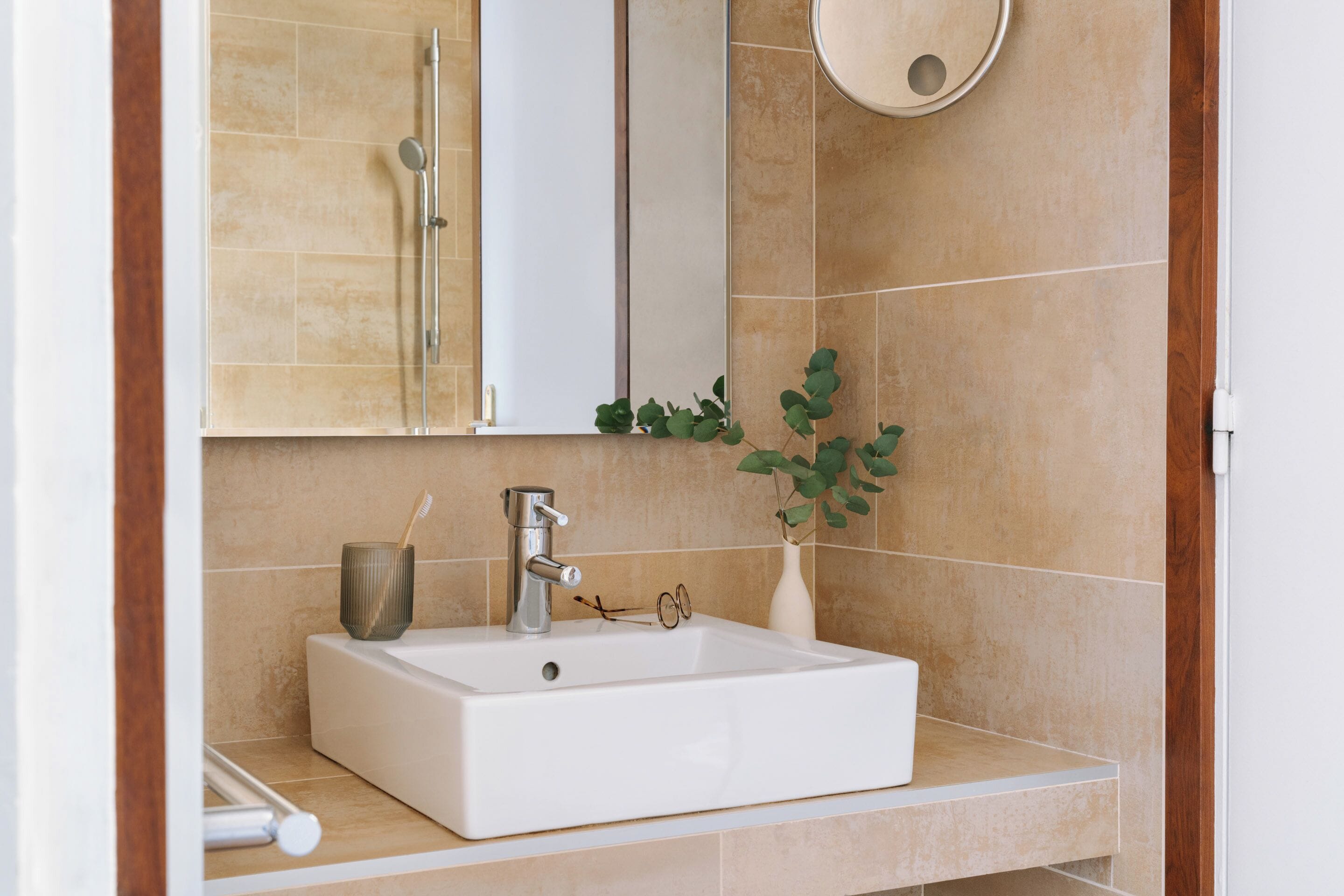 Een badkamer met een wit wastafel, een spiegel en een douche.