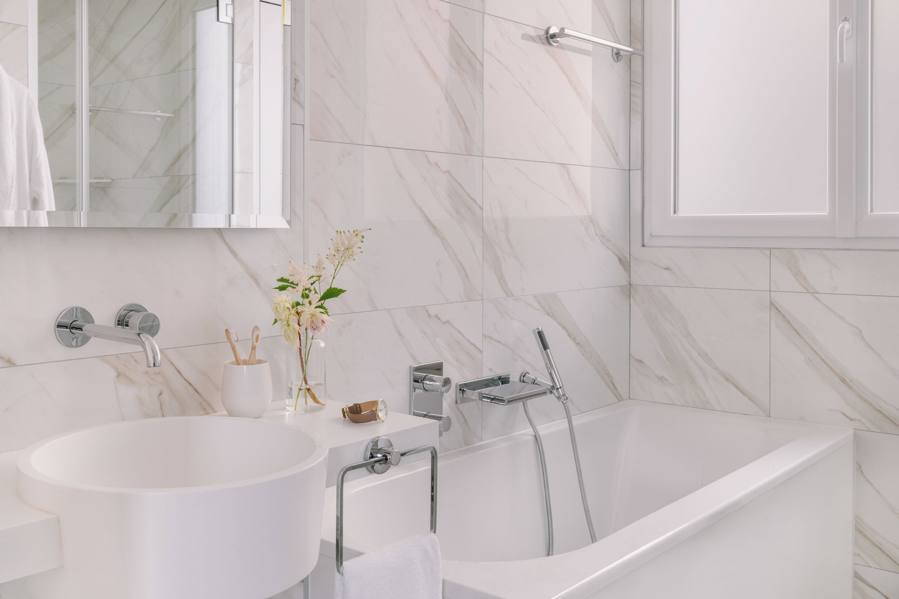 A modern bathroom with a freestanding bathtub, a wall-mounted sink, and a large mirror.