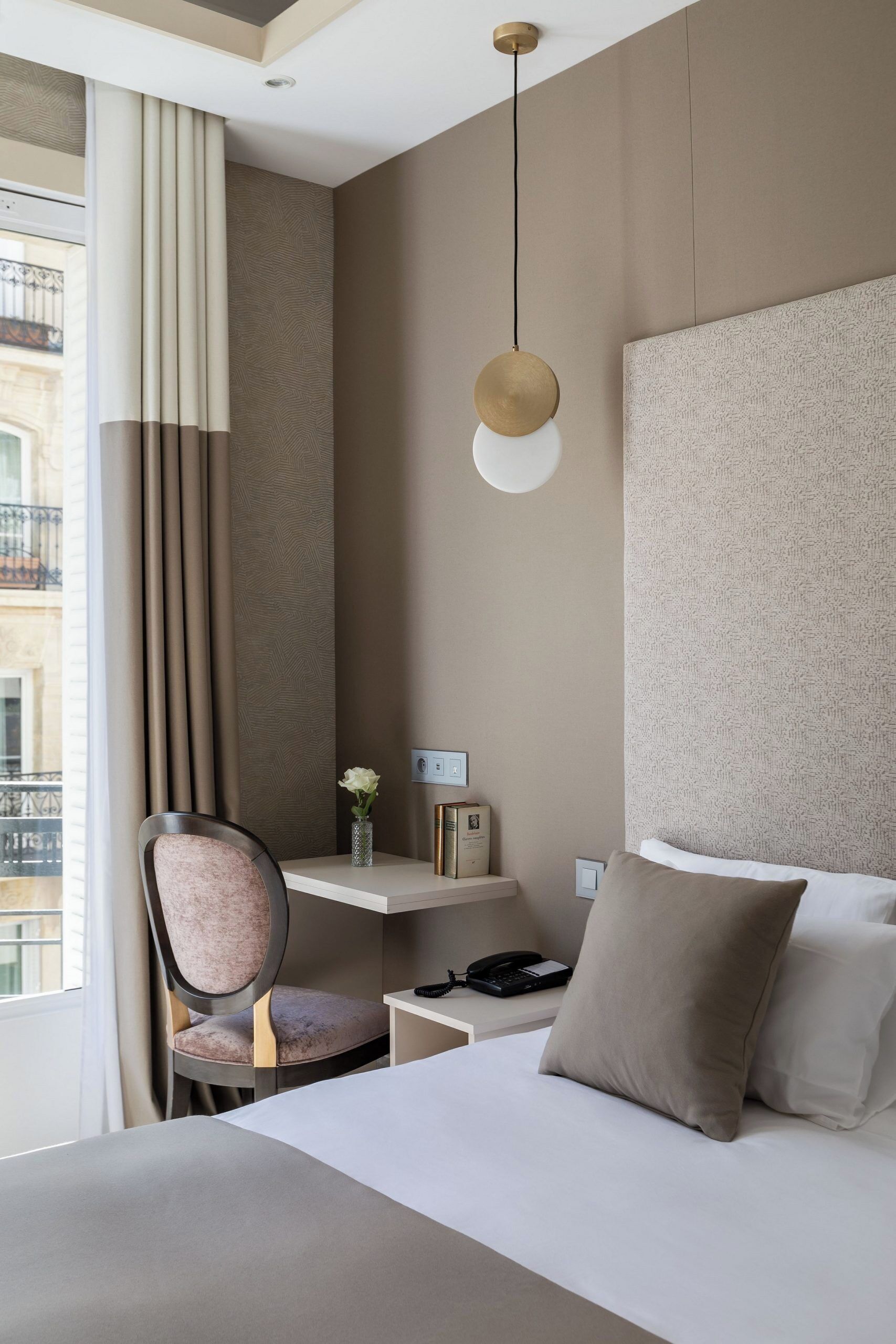 Una habitación de hotel con una cama, un escritorio, una silla y una ventana con cortinas.