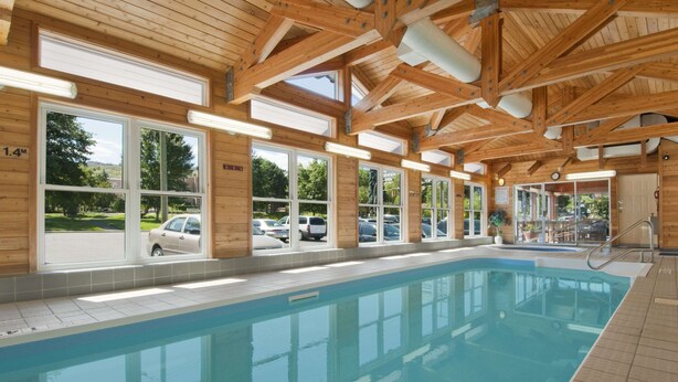 An indoor swimming pool with wooden beams and large windows. - Travelodge by Wyndham Kamloops (Kamloops)