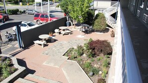 A courtyard with outdoor seating, a garden, and a parking area with cars. - Travelodge by Wyndham Kamloops (Kamloops)