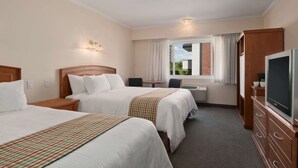 A hotel room with two beds, a desk, a television, and a window with curtains. - Travelodge by Wyndham Kamloops (Kamloops)