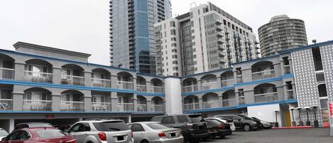 A hotel with multiple floors, balconies, and a parking lot with several cars.