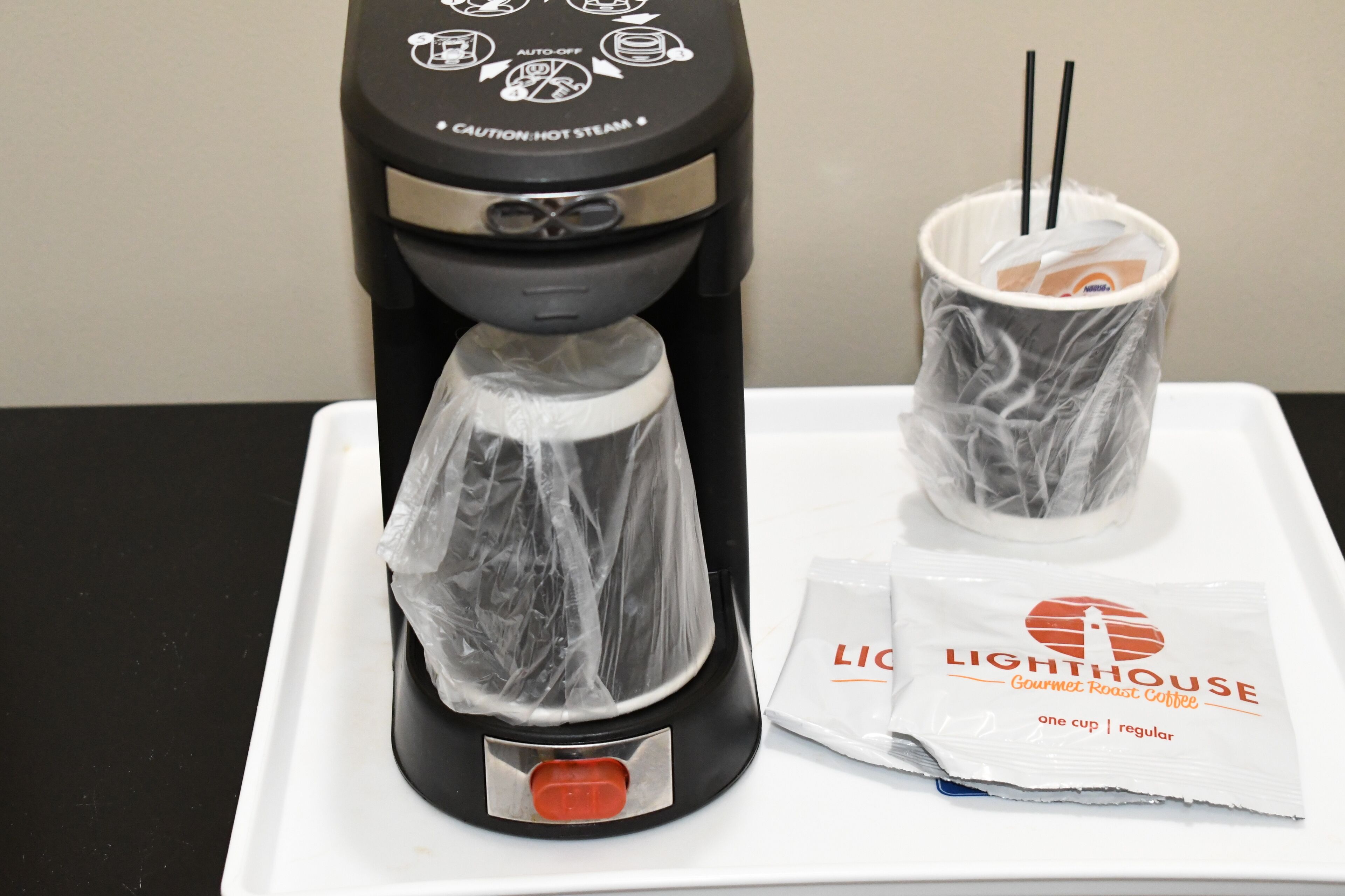 Uma cafeteira com duas chávenas de café, um pó de café e um sinal de aviso.