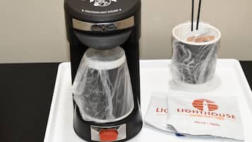 Uma cafeteira com duas chávenas de café, um pó de café e um sinal de aviso.