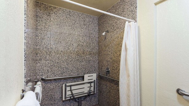 Ein Badezimmer mit Dusche, Haltegriffen und Handtuchhalter.