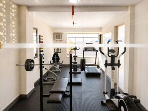 Uma academia com diversos equipamentos de exercício, incluindo esteira, elíptico e banco de musculação.