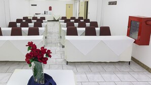 Un salón de conferencias con mesas y sillas dispuestas para reuniones.