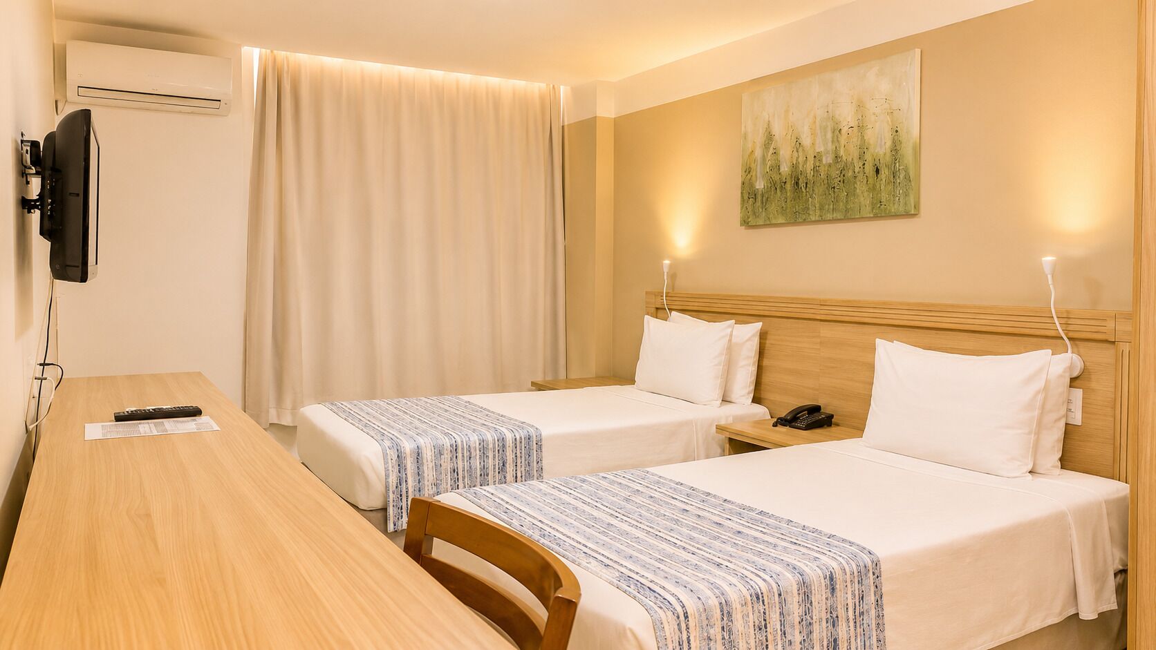 A hotel room with two beds, a desk, a TV, and a painting on the wall.