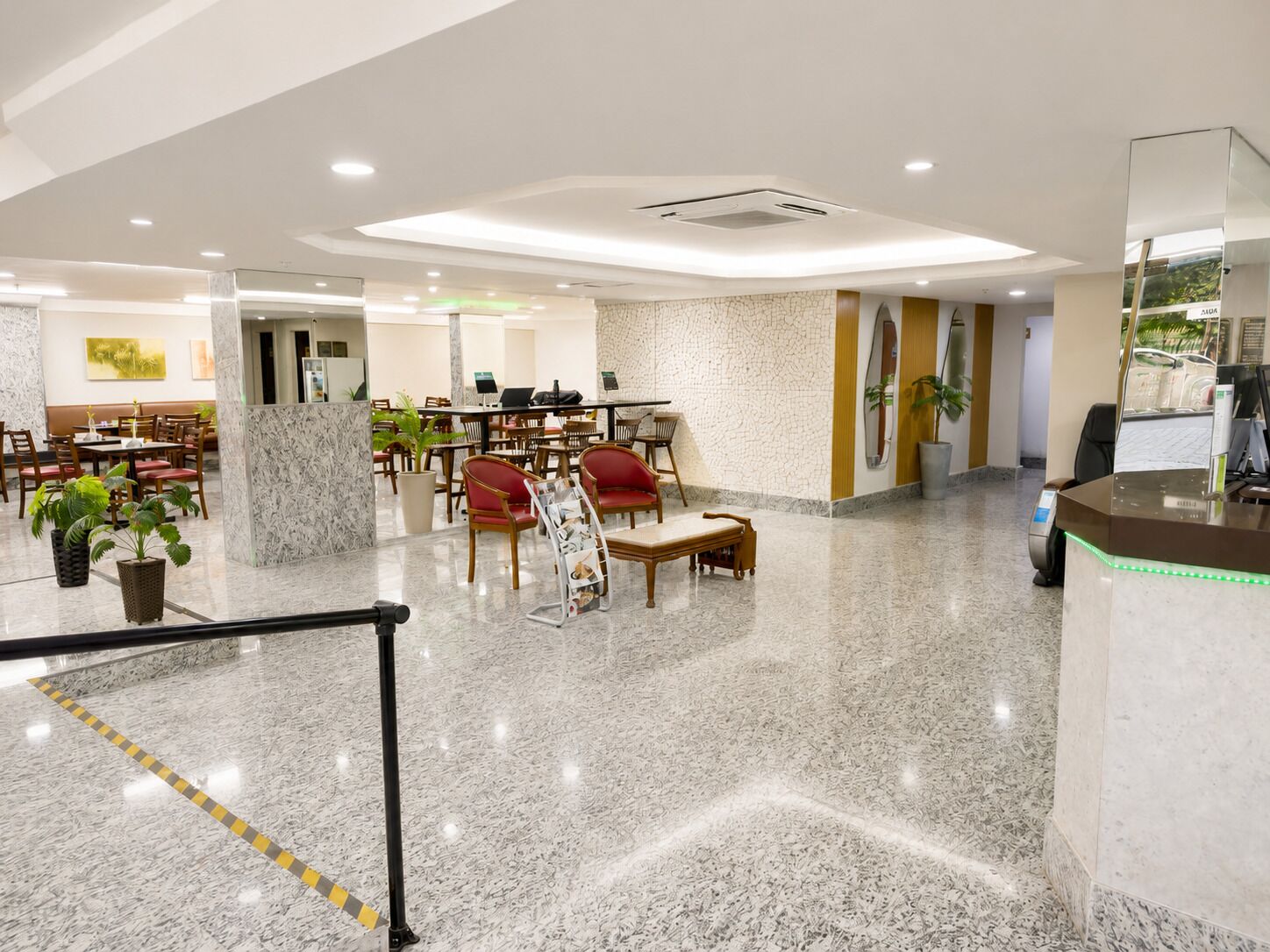 A hotel lobby with marble flooring, seating areas, a reception desk, and a wall-mounted surfboard.