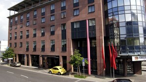 Un edificio moderno con múltiples ventanas y fachada de vidrio, y un cartel de estacionamiento.