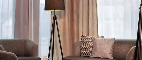 Una sala de estar moderna con un sofá, una mesa de centro, una lámpara de pie y cortinas translúcidas.