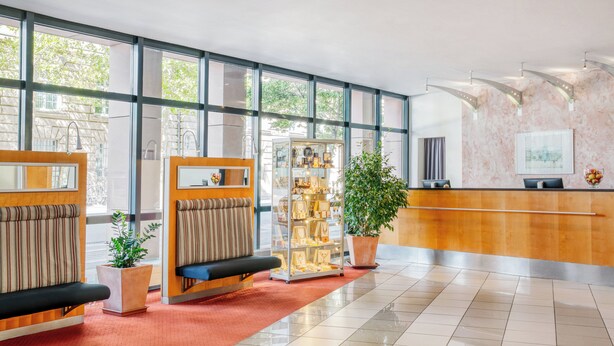 Un moderno vestíbulo de hotel con una recepción, zona de estar y una exposición de cuadros enmarcados.