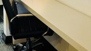A desk with a chair, a lamp, and a wall.