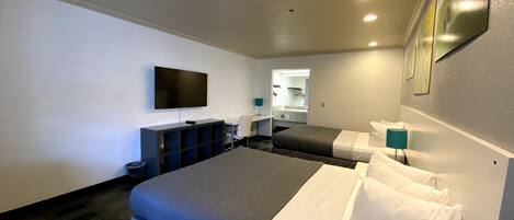 A hotel room with two beds, a flat-screen TV, a desk, and a mirror.