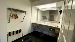 A bathroom with a vanity, a towel rack, a mirror, and a trash bin.