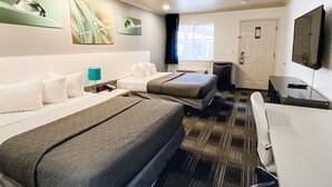 A hotel room with two beds, a desk, a chair, a TV, and artwork on the walls.