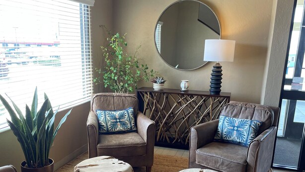A cozy living room with a large window, a round mirror, and two sofas with patterned cushions. - Mountain Home Inn (Mountain Home)