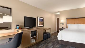 A hotel room with a bed, a desk with a computer, a television, a microwave, and a coffee maker.