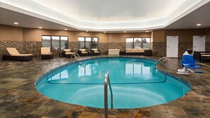 Una piscina interior con sillas de descanso y una pared de piedra.