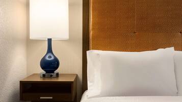 A neatly made bed with white linens and a headboard with a textured pattern.