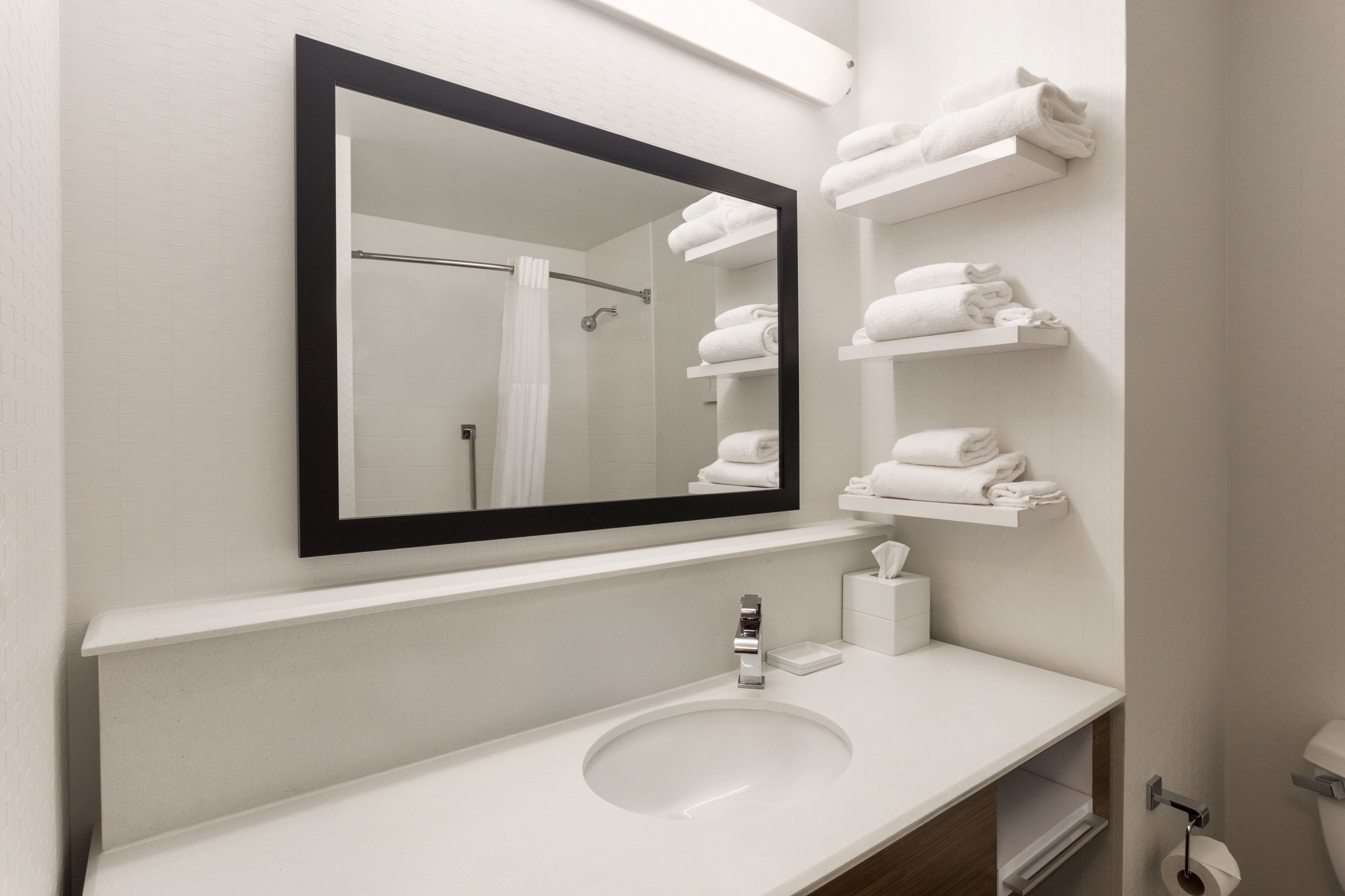 A bathroom with a white sink, a mirror, and a towel rack with folded towels.