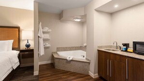 Habitación de hotel con cama, baño con bañera, lavamanos y microondas.
