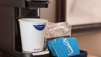 A coffee machine with a cup and a blue card on a tray.