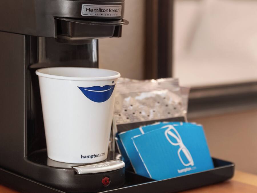 A coffee machine with a cup and a blue card on a tray.