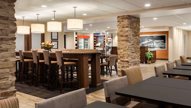 Un restaurante moderno con detalles en pared de piedra, varias mesas para comer y lámparas colgantes.