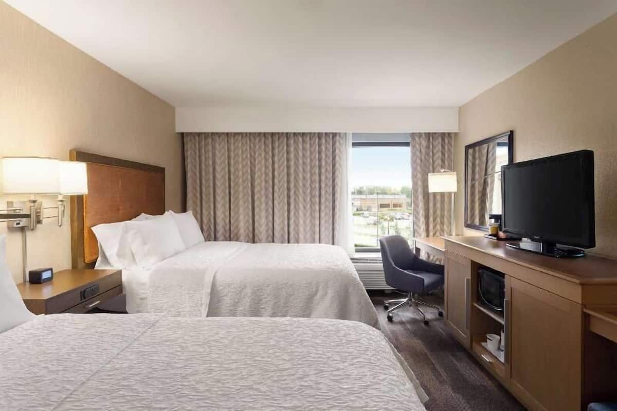 Une chambre d’hôtel avec deux lits, un bureau avec une télévision et une vue sur la ville.
