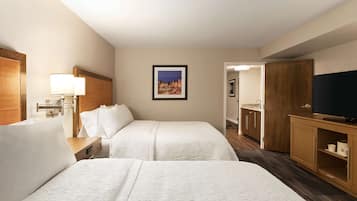 Habitación de hotel con dos camas, un televisor, un aparador de madera y un cuadro en la pared.