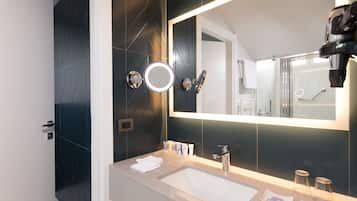 Un bagno moderno con uno specchio grande, un lavandino e una zona doccia.