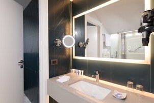 A modern bathroom with a large mirror, a sink, and a shower area.
