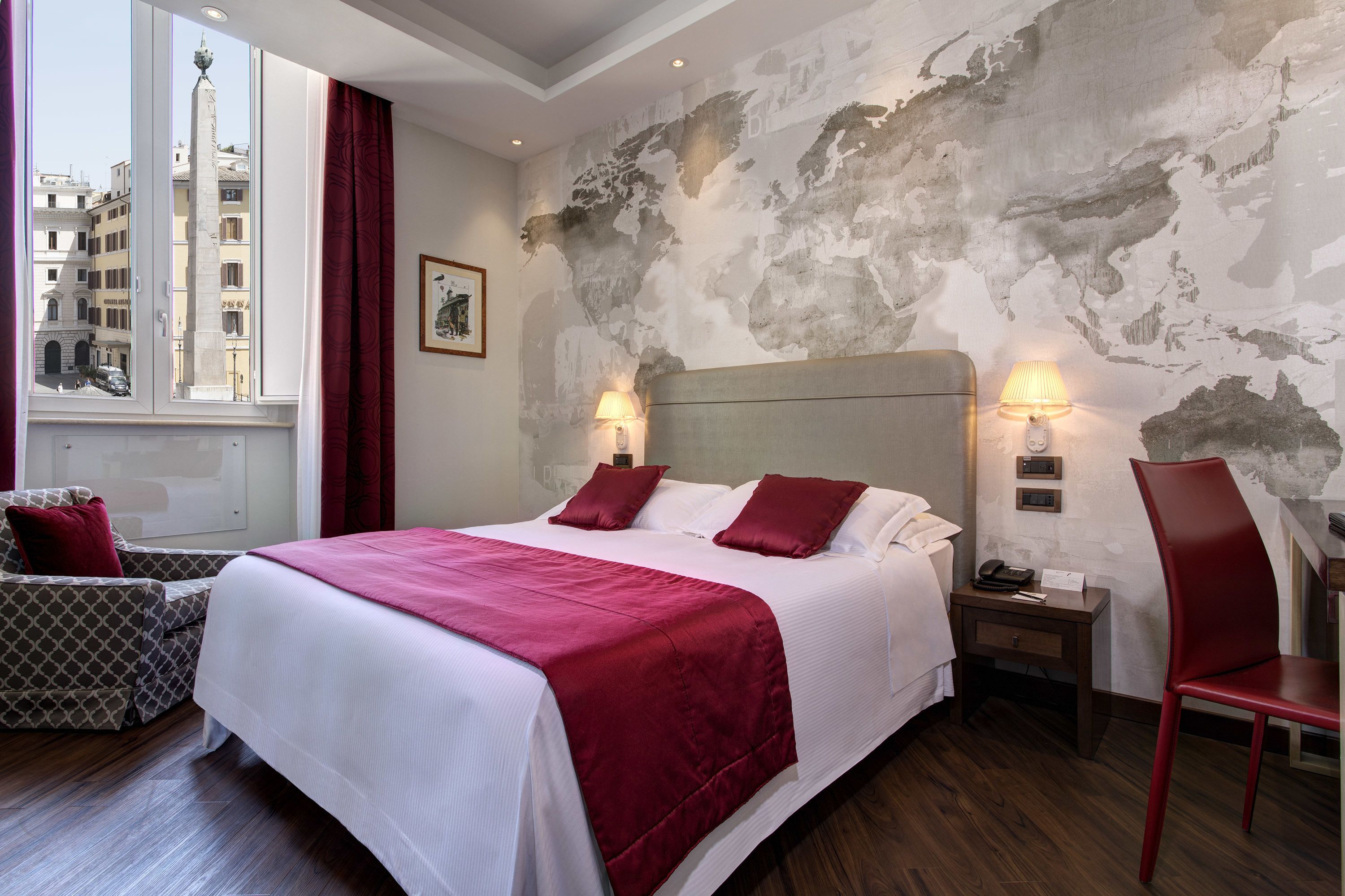 Hotelkamer met een groot bed, twee bedlampen, een nachtkastje, een stoel en uitzicht op een stadsgezicht door een raam.