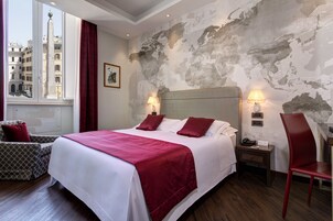 A hotel room with a large bed, two bedside lamps, a nightstand, a chair, and a view of a cityscape through a window.