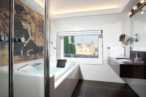 A modern bathroom with a glass-enclosed shower, a bathtub, and a window offering a city view.
