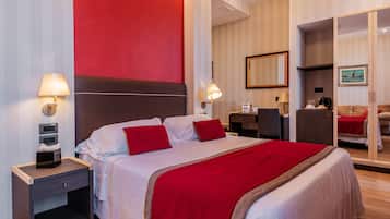 A hotel room with a large bed, a nightstand, a desk, and a wardrobe.